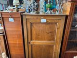 une grande armoire en bois sur laquelle sont disposés de nombreux vases en verre