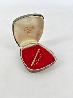 une petite boîte rouge contenant une pince à cravate argentée