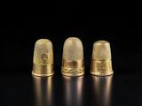 trois dés à coudre dorés sur un fond noir