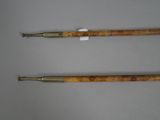 two wooden and brass canes with handles on a white surface