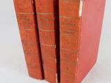 trois livres rouges sont empilés sur une surface blanche