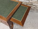 two tables with green leather tops sit in front of a brick wall