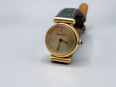 gros plan d'une montre-bracelet en or sur une surface blanche