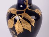 un vase bleu orné de feuilles dorées sur fond blanc