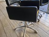 a black chair sitting in front of a window in a salon