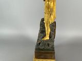 bronze statue of a man standing on a rock with a hat on top of his head