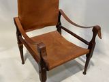 une image représentant un fauteuil en cuir marron posé sur un sol blanc