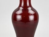 a red vase with a white top on a white surface