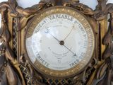 a gold clock with a barometer in the middle of it