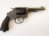 un vieux revolver posé sur une surface blanche, avec un fond blanc