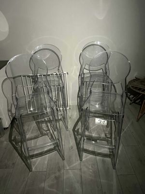 four clear chairs sitting next to each other on a wooden floor