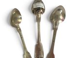 three spoons and a ladle are sitting on a white surface