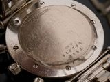 close up of a watch with a metal band on a black surface