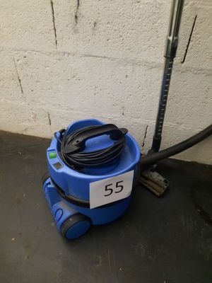 un gros plan d'un aspirateur bleu posé par terre à côté d'un tuyau