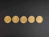 quatre pièces d'or sont disposées en ligne sur une surface noire