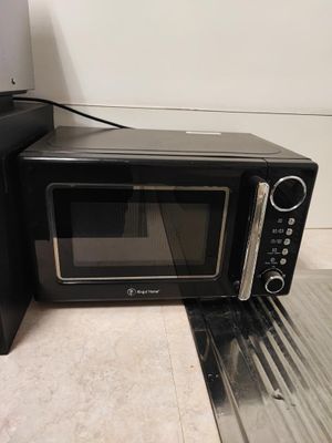 un four à micro-ondes noir posé par terre à côté d'un autre four à micro-ondes noir