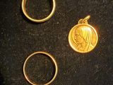 two gold rings and a gold coin sitting on a black cloth