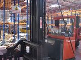 a forklift in a warehouse with pallets in the foreground