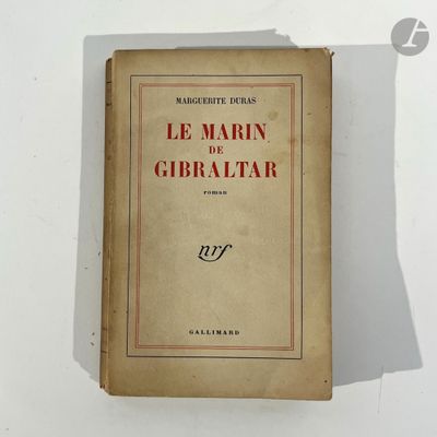 an old book sitting on top of a table next to a white wall