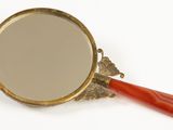 mirror with a red handle on a white surface with a white background