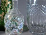 three glass vases and a glass bottle sitting on a table