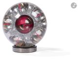 une boule rouge à l'intérieur d'un objet argenté posé sur un socle