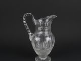 an antique glass pitcher with a handle on a black background