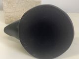 a black vase sitting on a table next to a stone block