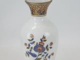 a white vase with blue flowers on it on a white surface