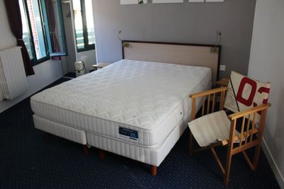 un lit et une chaise dans une pièce recouverte d'une moquette bleue