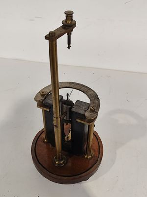 un petit objet métallique reposant sur un socle en bois, posé sur une surface blanche