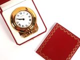 a small red box with a gold clock inside of it
