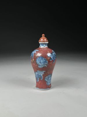 un vase rouge et bleu posé sur une table blanche