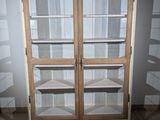 a wooden cabinet with glass doors in the corner of a room