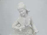 a white statue of a woman holding a fan