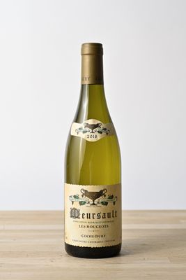 a bottle of white wine sitting on a wooden table
