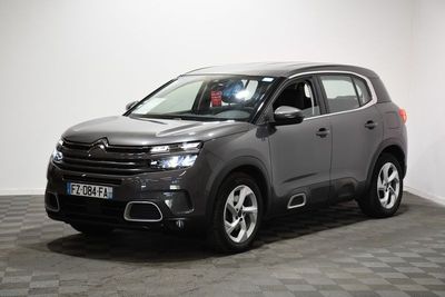 Une Citroën grise est garée dans une pièce au sol carrelé.