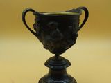 un vase noir orné d'un visage, posé sur une table