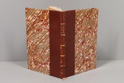 un livre à la couverture rouge posé sur une table blanche