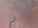 a rusted metal pan with a handle and a sign on it