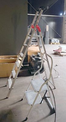 une échelle posée dans une pièce où se trouvent des cartons