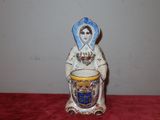 une figurine représentant une femme tenant une tasse
