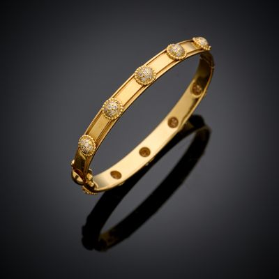 un bracelet rigide en or jaune serti de diamants sur un fond noir