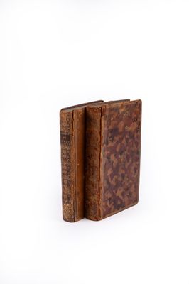 an old book with a leather cover sitting on top of a white surface