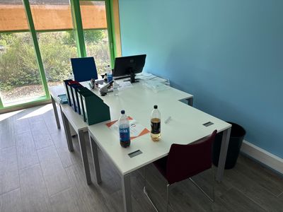 a white table with two laptops on it and a bottle of water on the table