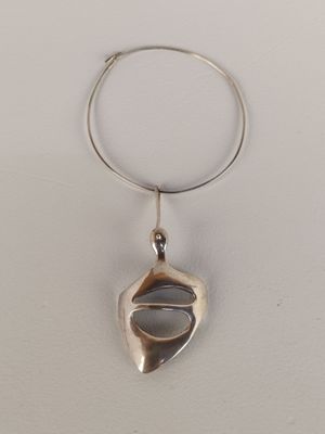 un gros plan d'une bague en argent à laquelle est accroché un pendentif en argent