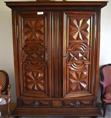 a wooden armoire in a room with a chair and a table
