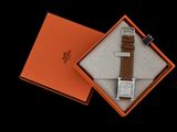 une boîte orange contenant une montre, posée sur une surface noire
