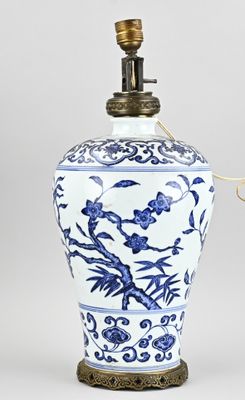 un vase bleu et blanc posé sur une table sur laquelle se trouve une lampe
