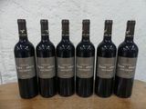 six bouteilles de vin rouge sont alignées sur une table en bois
